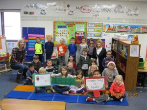 Excited kindergarteners happily show the sign of $913 for Komeka!